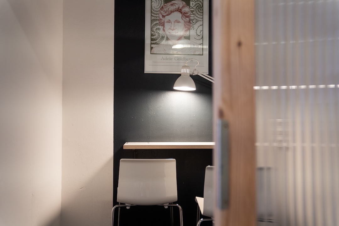 Blick in eine Telefonkabine mit Hochtisch, Licht und halbtransparenter Wand